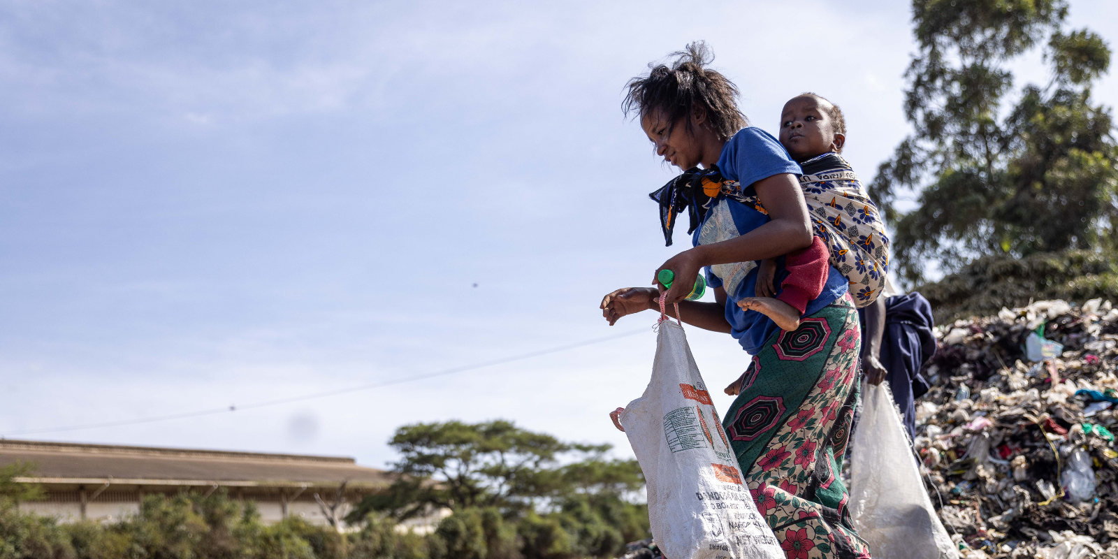 Woman carry's baby through dump